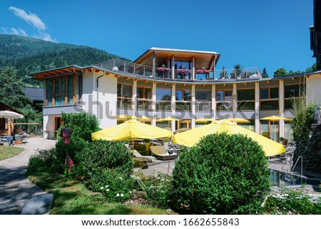 Modern hotel with swimming pool with yellow umbrellas on blue background. Poolside for relax. Summer fun and building architecture. Holiday and vacation on villa while travel or leisure time. 
