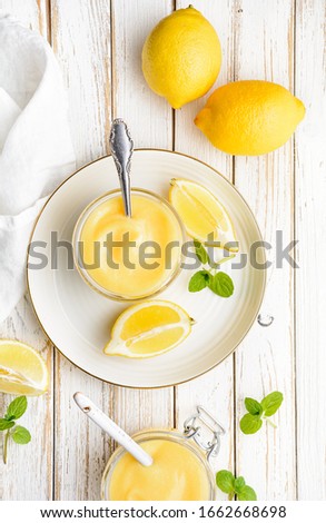 Delicious homemade tangy lemon curd decorated with fresh fruit in a glass jars on rustic wooden background Royalty-Free Stock Photo #1662668698