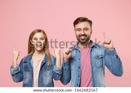 Excited bearded man in casual clothes with cute child baby girl. Father little kid daughter isolated on pastel pink background. Love family parenthood childhood concept. Pointing index fingers up