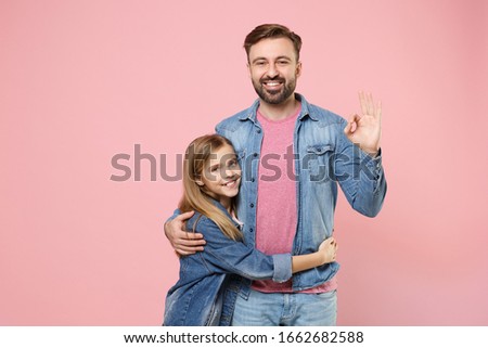 Smiling bearded man in casual clothes with child baby girl. Father little kid daughter isolated on pastel pink wall background. Love family parenthood childhood concept. Showing OK gesture, hugging