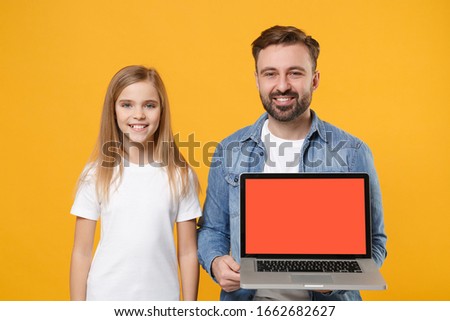 Smiling bearded man have fun with child baby girl. Father little kid daughter isolated on yellow background. Love family day parenthood childhood concept. Hold laptop computer with blank empty screen