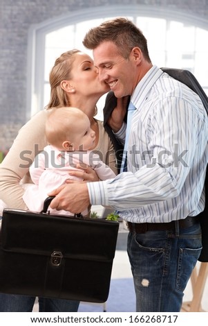 Businessman leaving for work, wife and baby daughter saying good-bye to him.