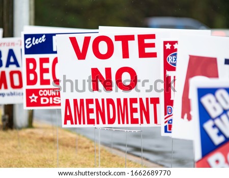Political sign urging Vote No Amendment within a sea of other annonomous political campaign signs on a rainy day.