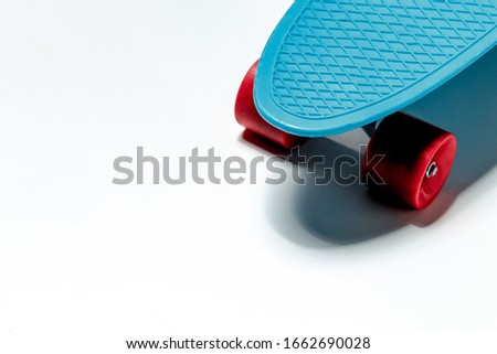 Blue skateboard cruiser with red wheels on white background with copy-space