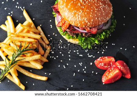 burger and fries on black background