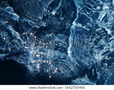 The​ pattern​ of​ surface​ blue​ water​ in​ the​ swimming​ pool​ reflected​ with​ sunlight​ for​ background​