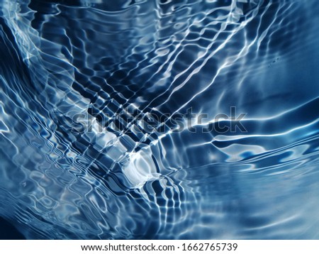 The​ pattern​ of​ surface​ blue​ water​ in​ the​ swimming​ pool​ reflected​ with​ sunlight​ for​ background​
