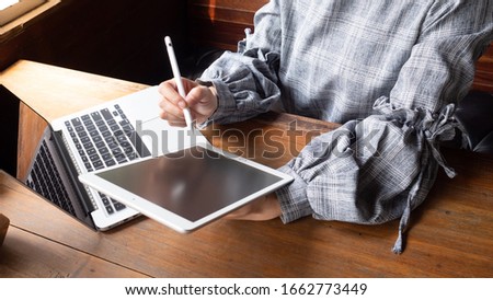 a business women is writing on tap-late. Financial charts and calculator on the table.