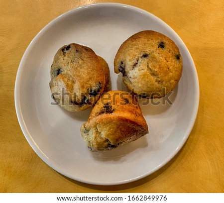 Three blueberry muffins o a plate.