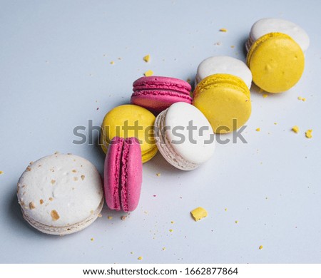 a few delicious colorful  macaron  with crumbs scattered around them are stacked on light gray background. 