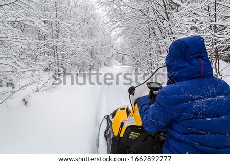 The girl on a snowmobile is guided by the GPS-navigator in the mountains of the Urals.