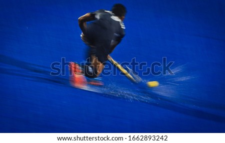 Slow shutter speed. Motion blur. The hockey player controls the ball on the field

