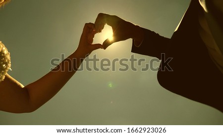 sun in hand. Silhouette of a loving couple making heart symbol with their hands opposite the sun on the horizon. teamwork of loving couple. Wedding day celebration