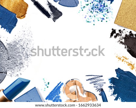 Crushed and smudged decorative cosmetics isolated on white forming a frame. A template with Copy space for a makeup artist's business card or flyer design. Samples of classic blue makeup products.