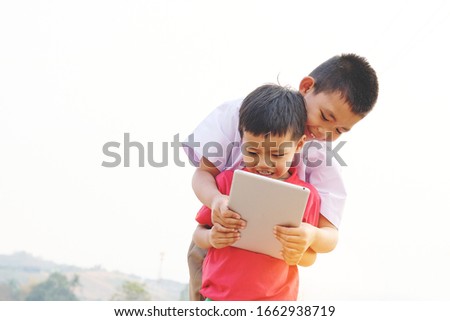 Concept happy asian kids lifestyle. Older brother and younger brother using tablet for entertains or learning together, technology,education concept.