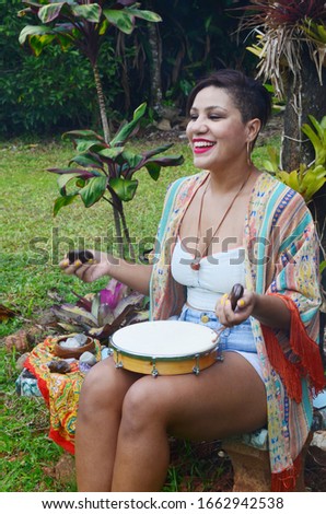 Beautiful Puerto Rican woman playing an instrument and singing outside. Puerto Rico music culture. Lovely woman enjoying music. Hispanic Hipster female, witchy vibes. Natural lighting portrait.
