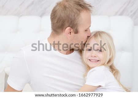 Close-up shot of young father kissing little smiling daughter. Sincere parents love