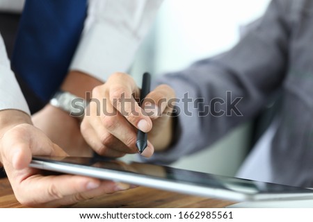 Man holds stylus and puts signature on tablet. Signing documents on an electronic touch device. Ability to quickly sign. Handle with special silicone tip. Ouch touch surface monitor