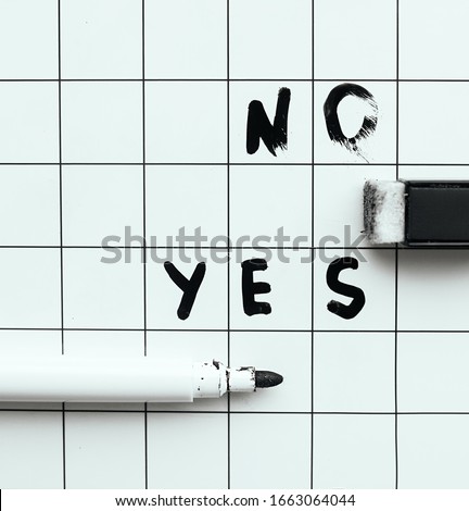 Lettering on a magnetic Board with a black marker that flushes out Yes or no. The choice of the word Yes.
