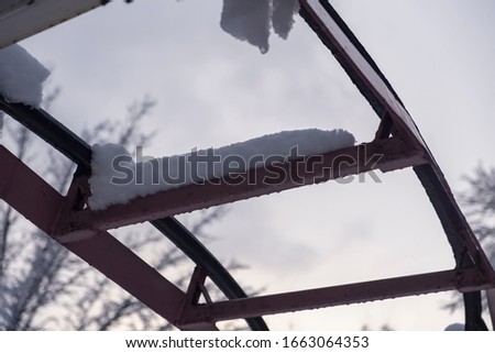 Roller coaster covered with snow in winter. Closed amusement park.