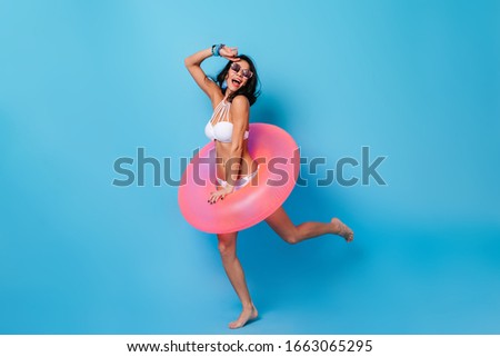 Active girl dancing in bikini. Full length view of graceful lady with swimming circle.