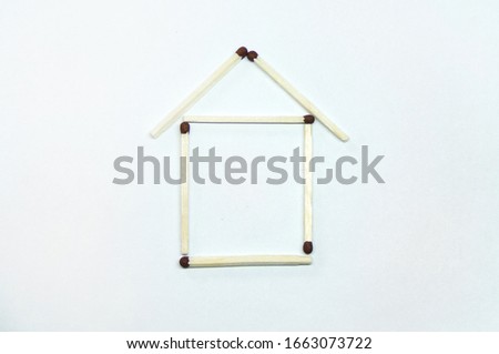 Icon of the house. The house is laid out of matches on a white background. The concept of building and buying a house. The house of matches is isolated on a white background in close -up.