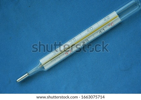 A medical mercury thermometer on blue background. High temperature. Blue background. Theme of health care, medical treatment and disease prevention.