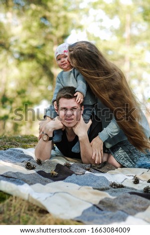happy family photo in the forest. mom, dad and little girl are having fun in nature. great family happiness. mom without makeup. natural feminine beauty. girl with very long hair
