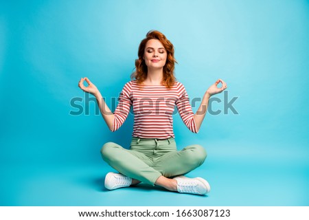 Full size photo of quiet serene woman sit floor crossed legs show om sign exercise yoga meditation wear stylish green outfit isolated over blue color background