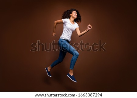 Full size profile photo of funny dark skin lady jumping high rushing black friday shopping store wear casual white t-shirt jeans isolated brown color background