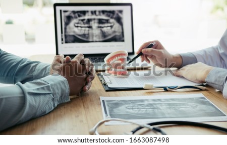 Dentists are discussing dental problems at report x-ray image on laptop screen to patients. Royalty-Free Stock Photo #1663087498