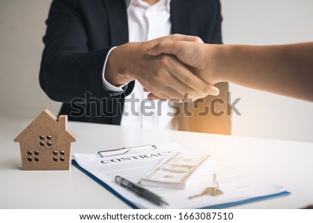 Home sales agents and buyers work on signing new homes and shaking hands.