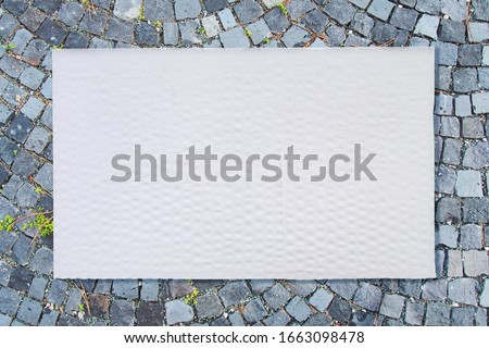 Blank for lettering call to action. The cardboard box board lying on the stone pavement background. Use in advertising, saying slogans for eco disign, construction topics, scandinavian topics.