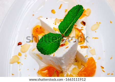 ice cream with nuts fruits and mint leaves on a white plate