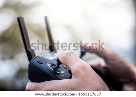 Close up hand of male tourist using remote of drone for exploring new places in forest