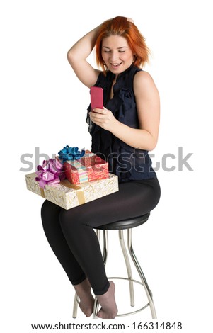 Happy red-haired woman with a gift box and a telephone on the white background