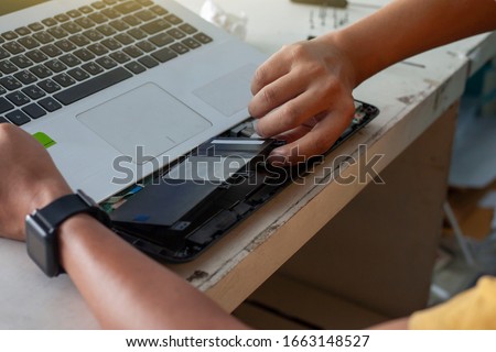 The technician is changing batteries to fix the laptop computer with Thai keyboard. Royalty-Free Stock Photo #1663148527