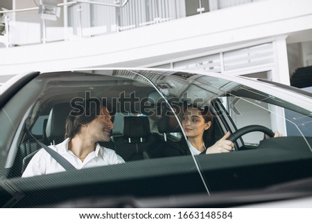 Man with woman in a car showroom choosing a car