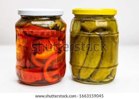 Glass jar with pickled red bell peppers and jar with pickled cucumbers (pickles) isolated. Royalty-Free Stock Photo #1663159045