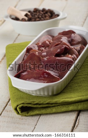 Raw chicken liver in bowl on white table. Selective focus.