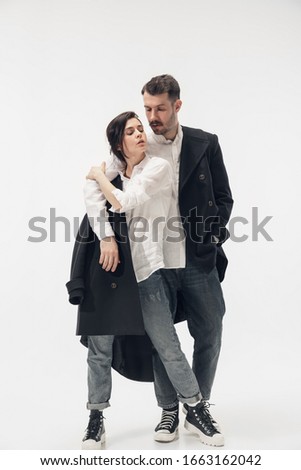 Near by. Trendy fashionable couple isolated on white studio background. Caucasian woman and man posing in basic minimal black stylish clothes. Concept of relations, fashion, beauty, love. Copyspace.