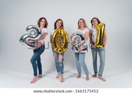 Beautiful pregnant girl in the white shirt and jeans holding the 2021 figures. The new year is 2021.