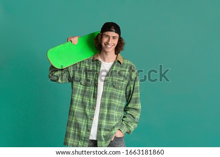 Teenage culture concept. Cool young man with skatebord on color background, space for text
