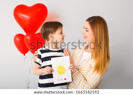 Little boy greeting his mother on light background