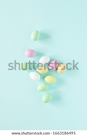 Easter minimal card with colored candy eggs on turquoise background. Top view.