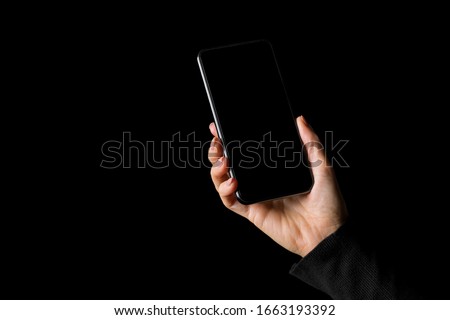 Person holding in hand mobile phone, isolated on black background