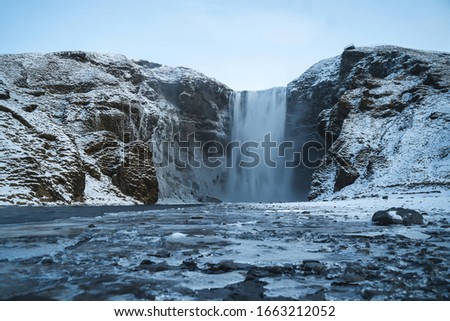 Skogafoss Waterfall in Icelandic Cold Winter. Beautiful Fall. Snowy Background.