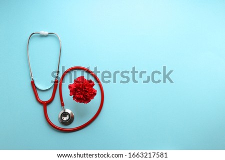 Still life red stethoscope and red carnation on a blue background symbolize the day of the doctor Royalty-Free Stock Photo #1663217581