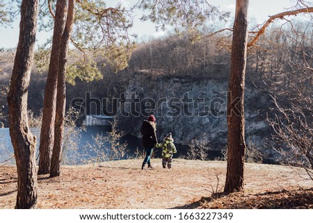 mom hugs son on the background of the river in autumn
