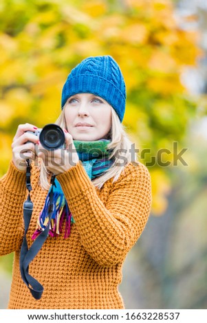 Portrait of beautiful woman photographing lovely maple trees in park